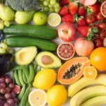 A colorful assortment of fruits and vegetables including carrots, spinach, blueberries, tomatoes, and oranges