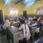 Assam Police officers conducting a cybercrime awareness session in a semi-urban college classroom with students attending.