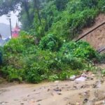 Flooded residential streets in Silchar Assam with vehicles struggling to move through severe monsoon waterlogging.