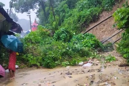 Flooded residential streets in Silchar Assam with vehicles struggling to move through severe monsoon waterlogging.