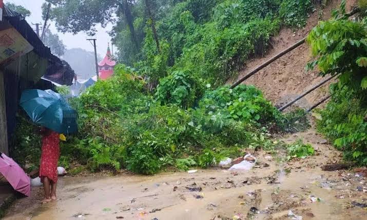 Flooded residential streets in Silchar Assam with vehicles struggling to move through severe monsoon waterlogging.