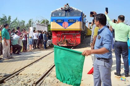 Train undergoing trial run on Agartala-Akhaura international railway line with engineers monitoring safety systems and track performance.