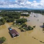 Floodwaters from the overflowing Brahmaputra River inundate residential areas in Jorhat as thousands of residents evacuate following widespread monsoon flooding.