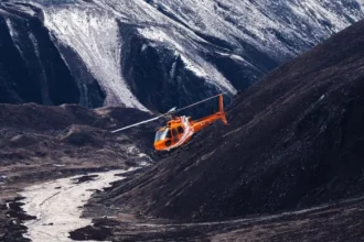 An emergency rescue helicopter prepares for a medical evacuation mission in a mountainous region where road access has been disrupted by severe monsoon conditions.