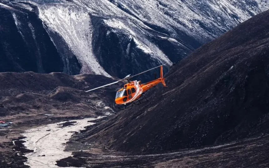 An emergency rescue helicopter prepares for a medical evacuation mission in a mountainous region where road access has been disrupted by severe monsoon conditions.